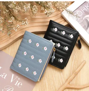 Close-up detail of small women's embroidered flower wallets in black and light blue PU leather