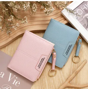 Gros plan de portefeuilles courts zippés roses et bleus avec texture litchi et porte-clés.