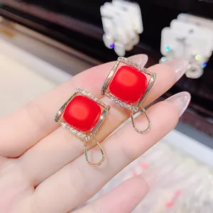 Detailed view of square red matte stud earrings with crystal pavé and gold finish