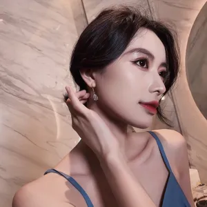 Elegant pear-shaped drop earrings worn by a model in a luxury indoor setting
