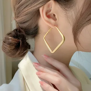 Close-up detail view of a large matte gold geometric diamond hoop earring on an Asian model