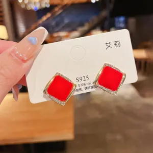 Close-up of red matte square earrings with rhinestone borders on S925 card