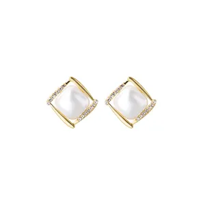 Detailed macro view of elegant gold geometric stud earrings featuring centered square pearl