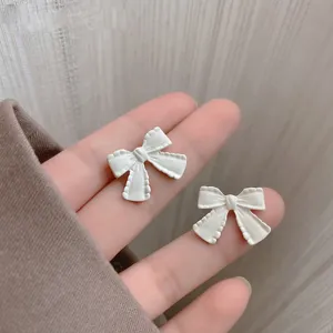 Detailed macro view of minimalist white matte bow-shaped stud earrings accessories