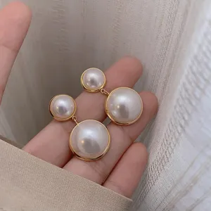 Elegant double pearl drop earrings with gold-toned plating for women shown held in hand