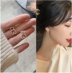 Close-up detail showing the elegant pearl bear stud earrings with a gold bow-knot design
