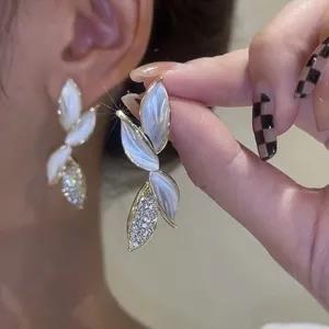 Detail shot of elegant leaf-shaped earrings with pearlescent petals and crystals