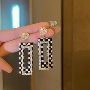 Primer plano de pendientes largos de damero en blanco y negro con brillantes strass