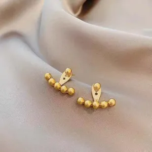 Detailed macro shot of elegant minimalist golden beaded arch earrings on silk fabric