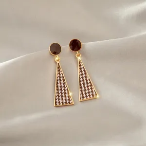 Detail shot of elegant houndstooth pattern triangular dangle earrings on grey silk