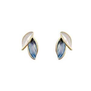 Detailed view of elegant gold-framed leaf earrings with white and blue enamel finish