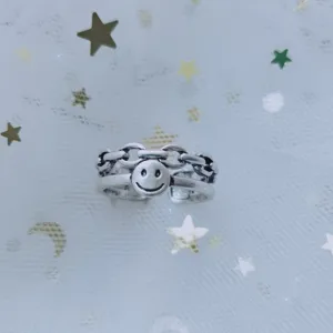 Detailed view of a silver-tone smiley face charm ring with chain-link band design