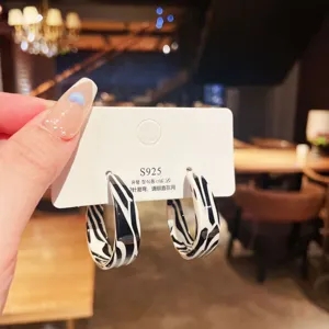 Macro detail showing zebra pattern enamel hoop earrings with S925 silver needle hallmark.