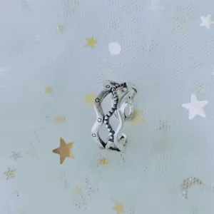 Close-up of vintage silver hollow wavy open ring on starry mesh fabric