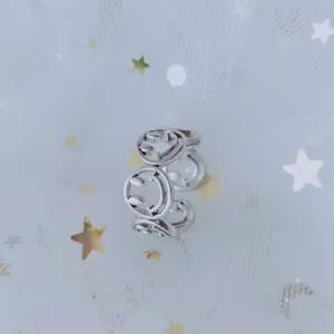Close-up of a trendy silver-toned open ring with smiley face motifs on starry mesh fabric