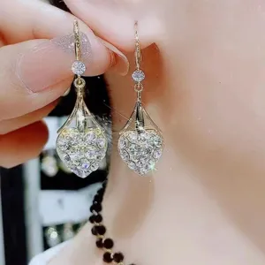 Vista dettagliata di orecchini pendenti a forma di cuore con cristalli pavé in oro