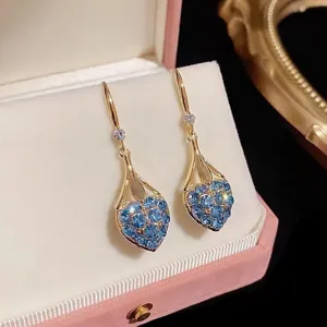Eleganti orecchini pendenti in oro con cuori di strass blu in un astuccio rosa.