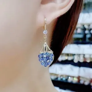 Dettaglio ravvicinato di orecchini a cuore blu con strass luminosi sull'orecchio