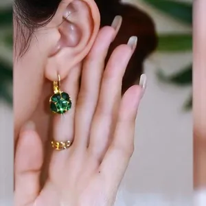 Detail shot of elegant green faceted crystal ball drop earrings worn on an earlobe