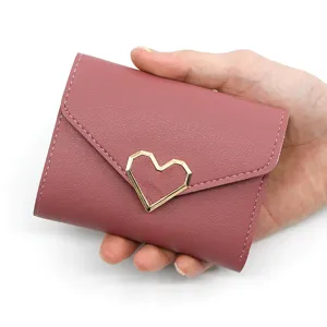 Elegant pink short tri-fold women's wallet featuring a gold geometric heart-shaped buckle