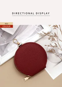Close-up of a circular red pebbled leather coin purse with golden zipper details.