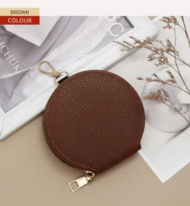 Close-up of a brown circular pebbled leather coin purse with a gold zipper and clip hook.