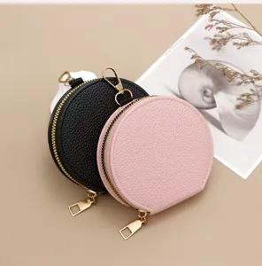 Detail shot of round pebble leather coin purses in black and pink with gold hardware.