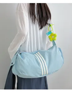 Detailansicht einer hellblauen Sporttasche mit drei weißen Streifen und gelbem Blumenanhänger