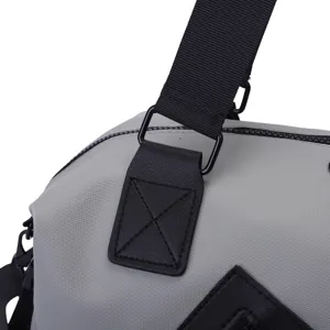 Détail de la fixation de la bandoulière et des coutures renforcées sur un sac de voyage gris