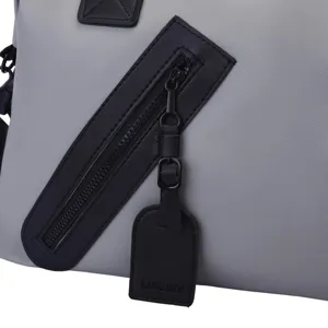 Gros plan détaillé de la fermeture éclair et de l'étiquette en cuir noir sur un sac de voyage gris