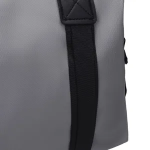 Gros plan sur le tissu en nylon durable et la sangle renforcée du sac de voyage gris.