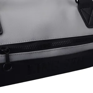 Détail d'un sac de sport gris avec fermeture éclair noire et logo LING SEN embossé