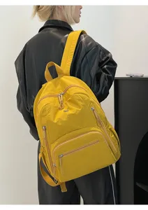 Détail d'un grand sac à dos en nylon jaune imperméable porté par un mannequin stylé