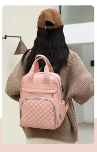 Detailed back view of a pink quilted mummy backpack worn over a stylish brown sweater