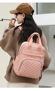 Back view of a model wearing a stylish pink quilted diaper backpack for mothers