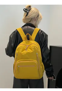 Sac à dos en nylon jaune imperméable avec plusieurs poches zippées porté par un modèle