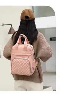 Stylish pink quilted mommy backpack with dual handles and large capacity shown on model.