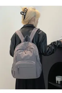 Sac à dos gris durable en nylon imperméable avec poches zippées multiples porté par modèle