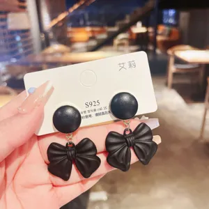 Detail view of elegant black bow drop earrings with S925 silver needles on a display card