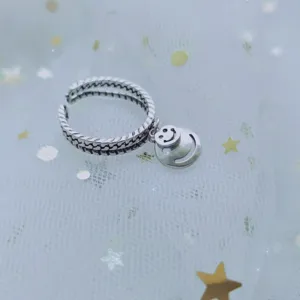 Detailed view of silver chain-style open ring with a dangling smiley face charm