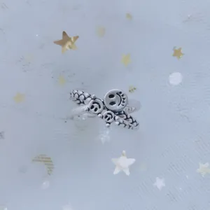 Detail of silver smiley face adjustable open ring on star patterned mesh background