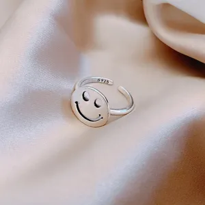 Macro detail of a minimalist silver smiley face ring with S925 engraving on silk fabric