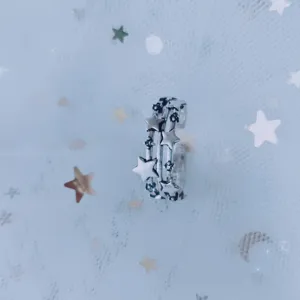 Close-up detail of silver-tone multi-layer ring featuring celestial star patterns.