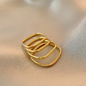Detail shot of four stacked gold square minimalist rings with small inset zircons.