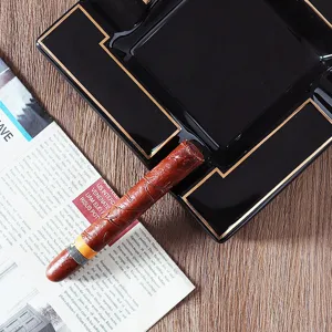 Detail of black melamine square cigar ashtray with elegant gold trim and cigar slot
