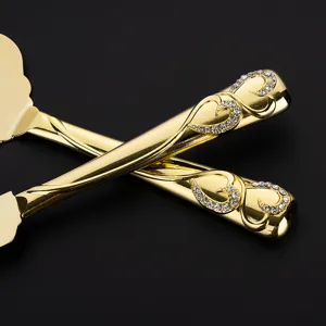 Nahaufnahme von luxuriösen goldenen Tortenmessergriffen mit herzförmigen Strassdetails.