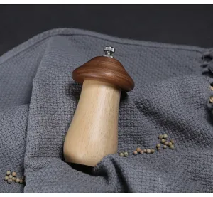 Detailed close-up of a mushroom-shaped wooden pepper grinder on a soft grey fabric