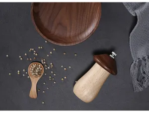 Close-up of a cute mushroom-shaped wooden pepper grinder on a dark textured table.