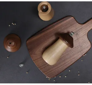 Close-up top view of a mushroom shaped solid wood pepper grinder on a wooden cutting board