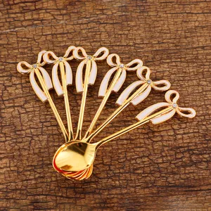 Elegant golden dessert spoon set with bow-knot design and rhinestone inlay on wood